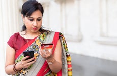 Woman looking at credit card and holding smartphone