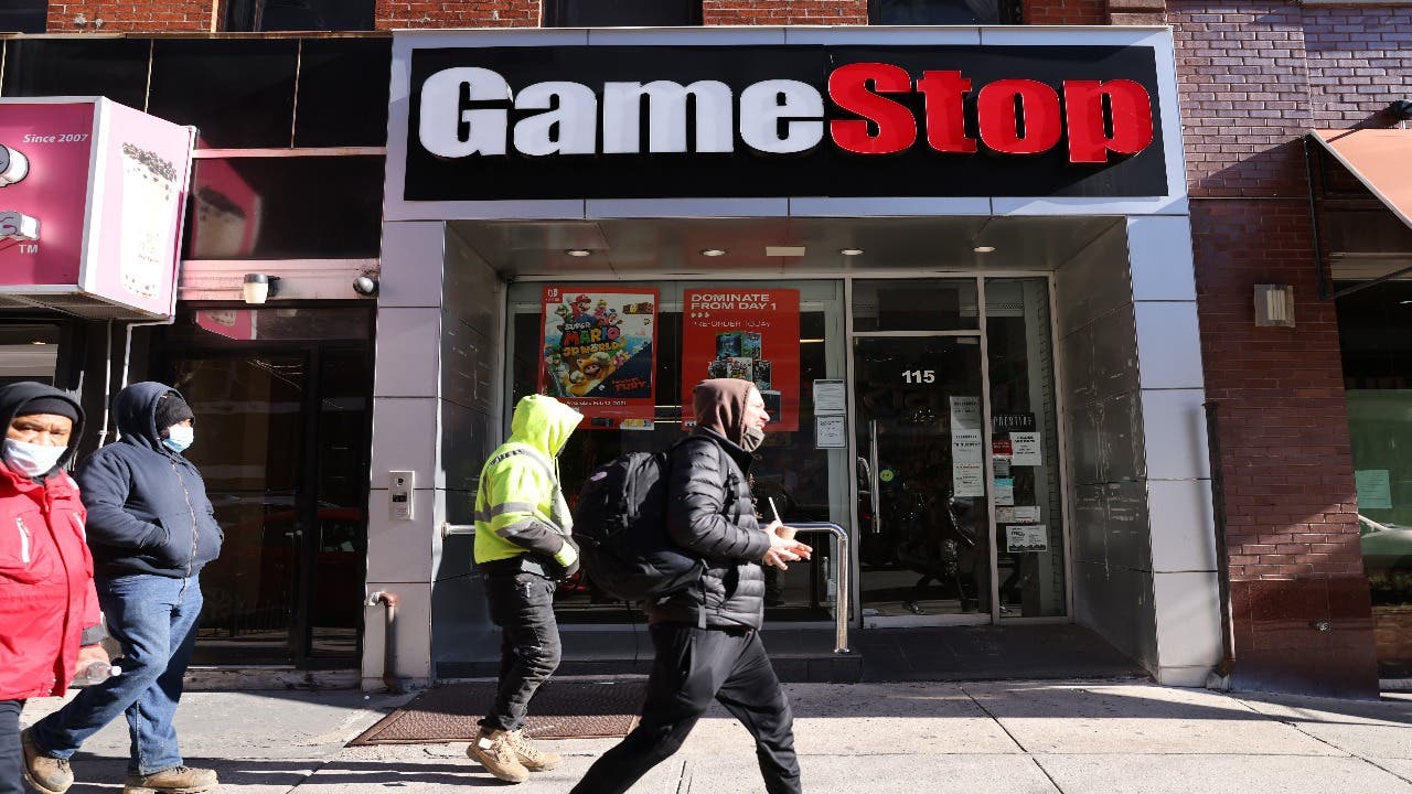 A few pedestrians pass in front of a GameStop store