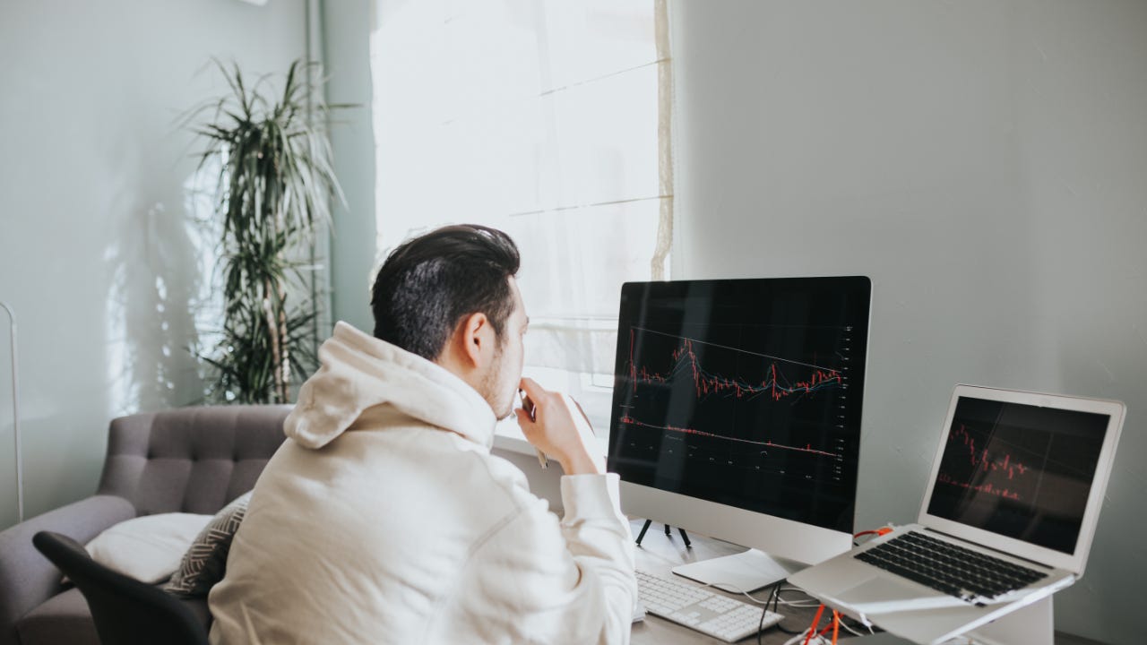 A man sits at his computer looking at a stock chart