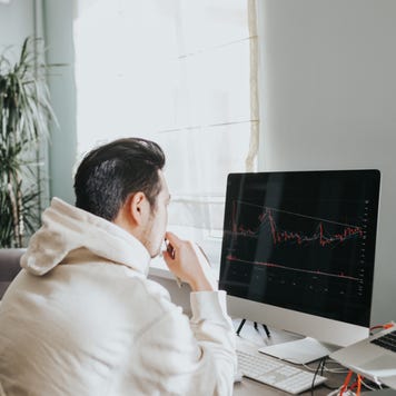 A man sits at his computer looking at a stock chart