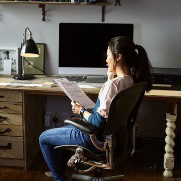 A woman is sitting in her home office on the phone with her auto insurance provider