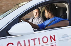 A young black man is in a student driver car with his teacher