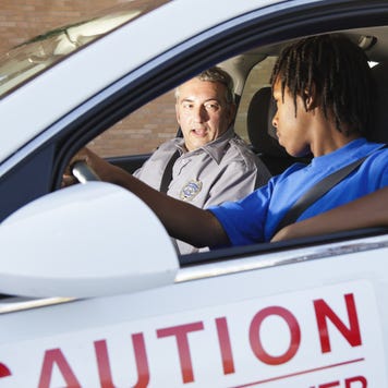 A young black man is in a student driver car with his teacher