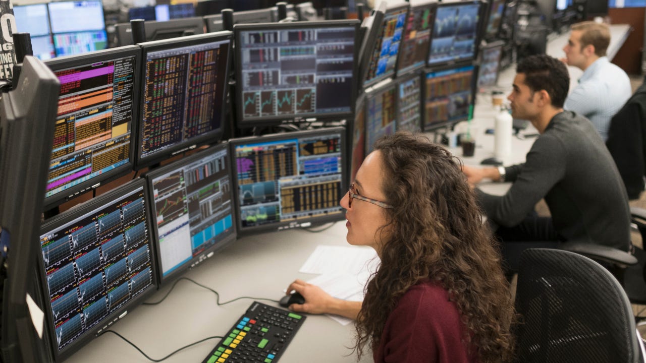 A young trader looks at computer screens full of securities