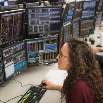 A young trader looks at computer screens full of securities