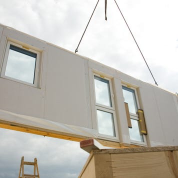 A piece of a modular home being installed via crane