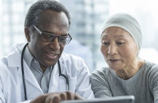 An Asian woman recovering from cancer looking at options with a physician