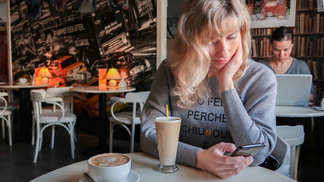 A young woman uses her smartphone while at a cafe.
