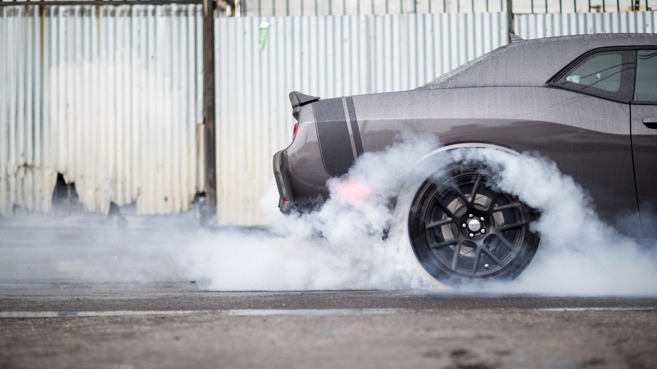 A sports car peeling out with smoke rising from the wheels and concrete