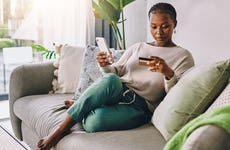 woman sitting on couch looking at credit card