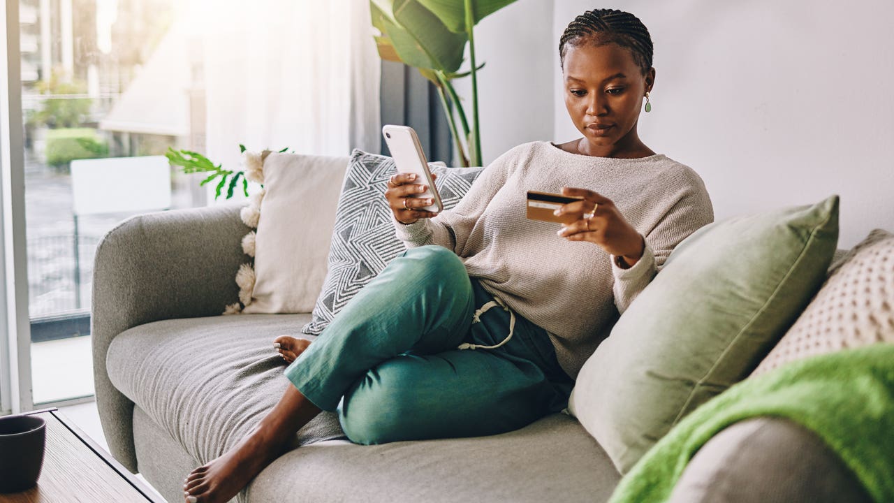 woman sitting on couch looking at credit card