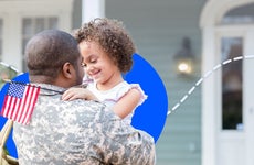 A young girl smiles while hugging her Army dad.