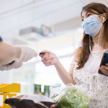 Woman using credit card to pay for grocery purchase