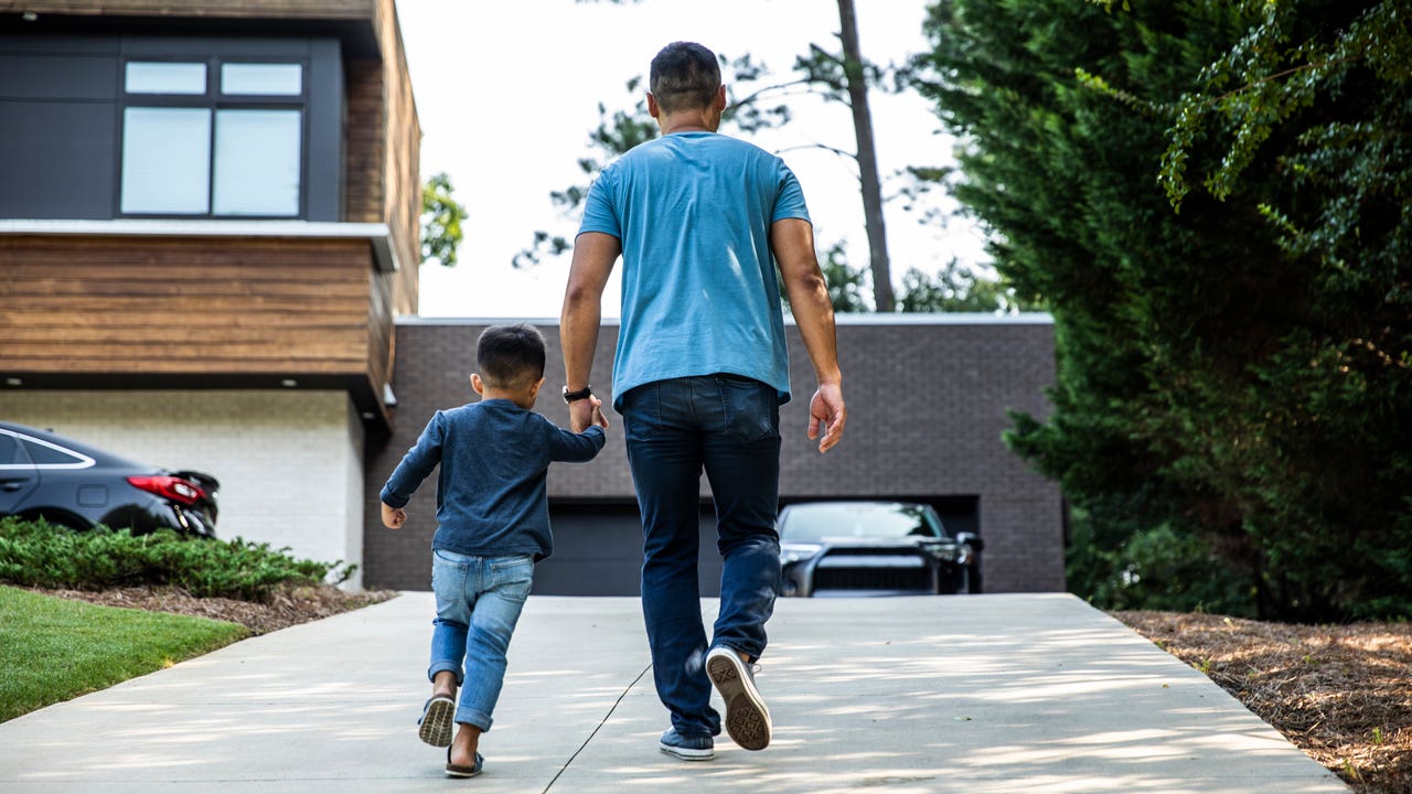 father and son walking up driveway to house