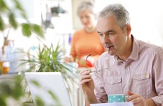 Older couple at home, man with laptop