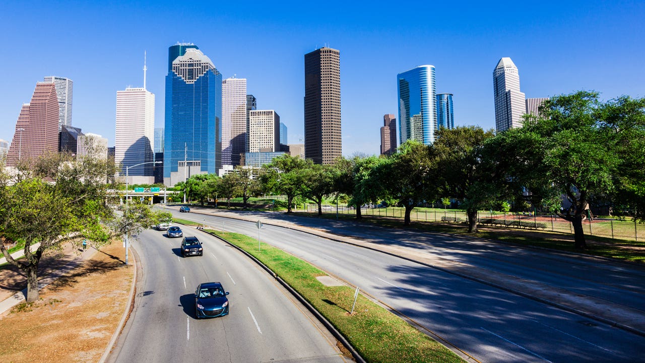 A busy freeway in Texas with buildings in the background.