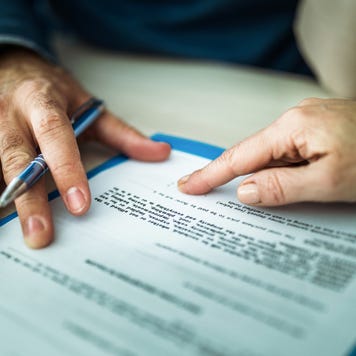 Paper document on table with two individuals' hands showing reviewing the document.