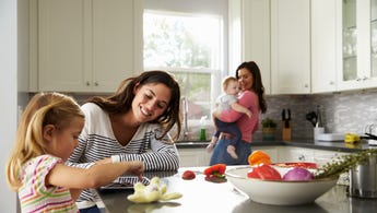 Two mothers in kitchen with their children