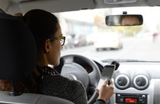 Woman in car looking at smartphone