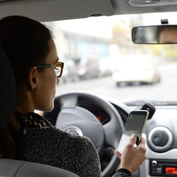 Woman in car looking at smartphone