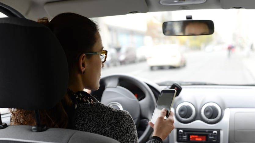 Woman in car looking at smartphone