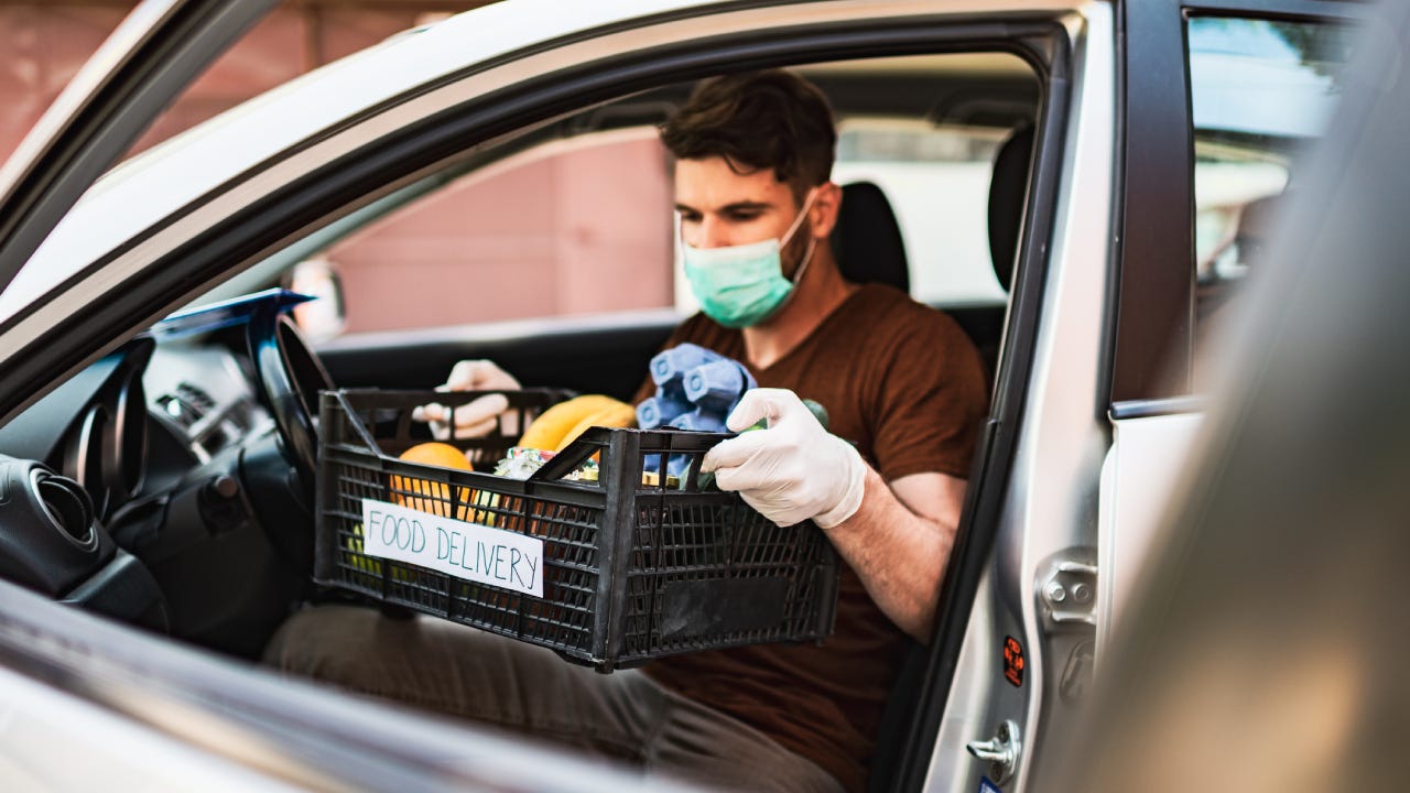 Delivery guy with protective mask and gloves delivering groceries during lockdown and pandemic