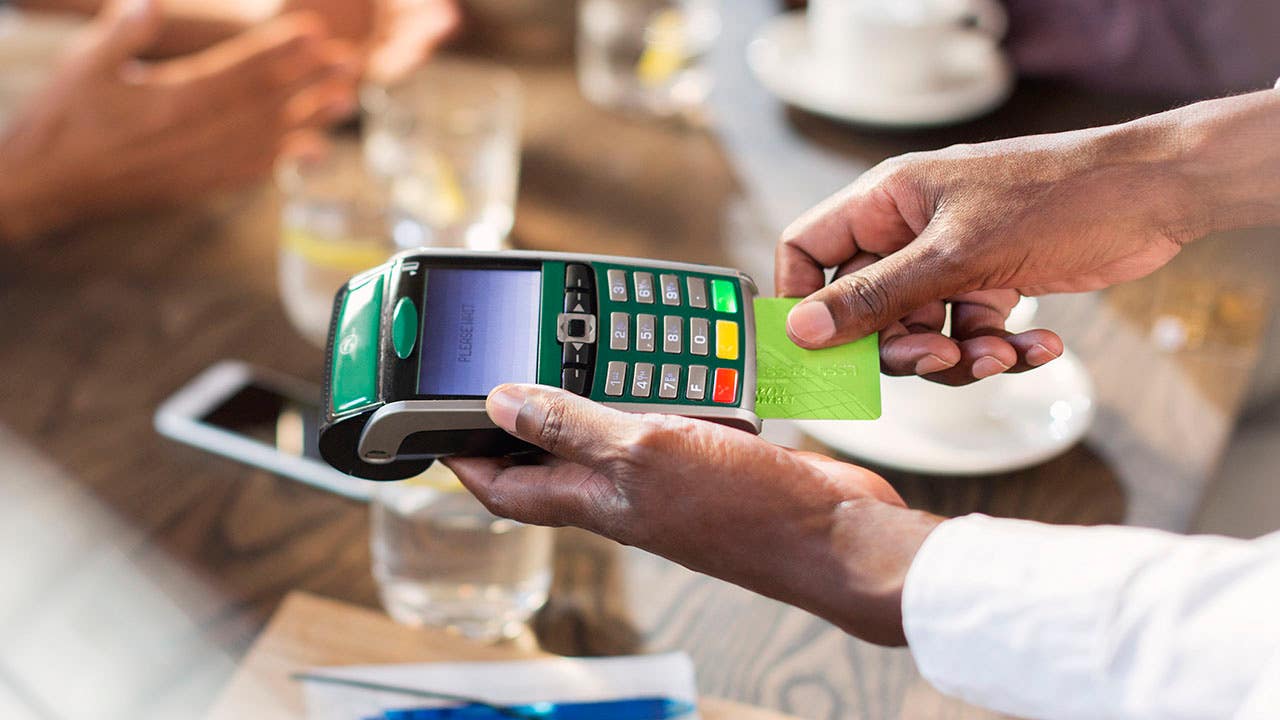 Waiter using credit card reader at restaurant table