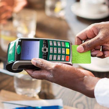 Waiter using credit card reader at restaurant table