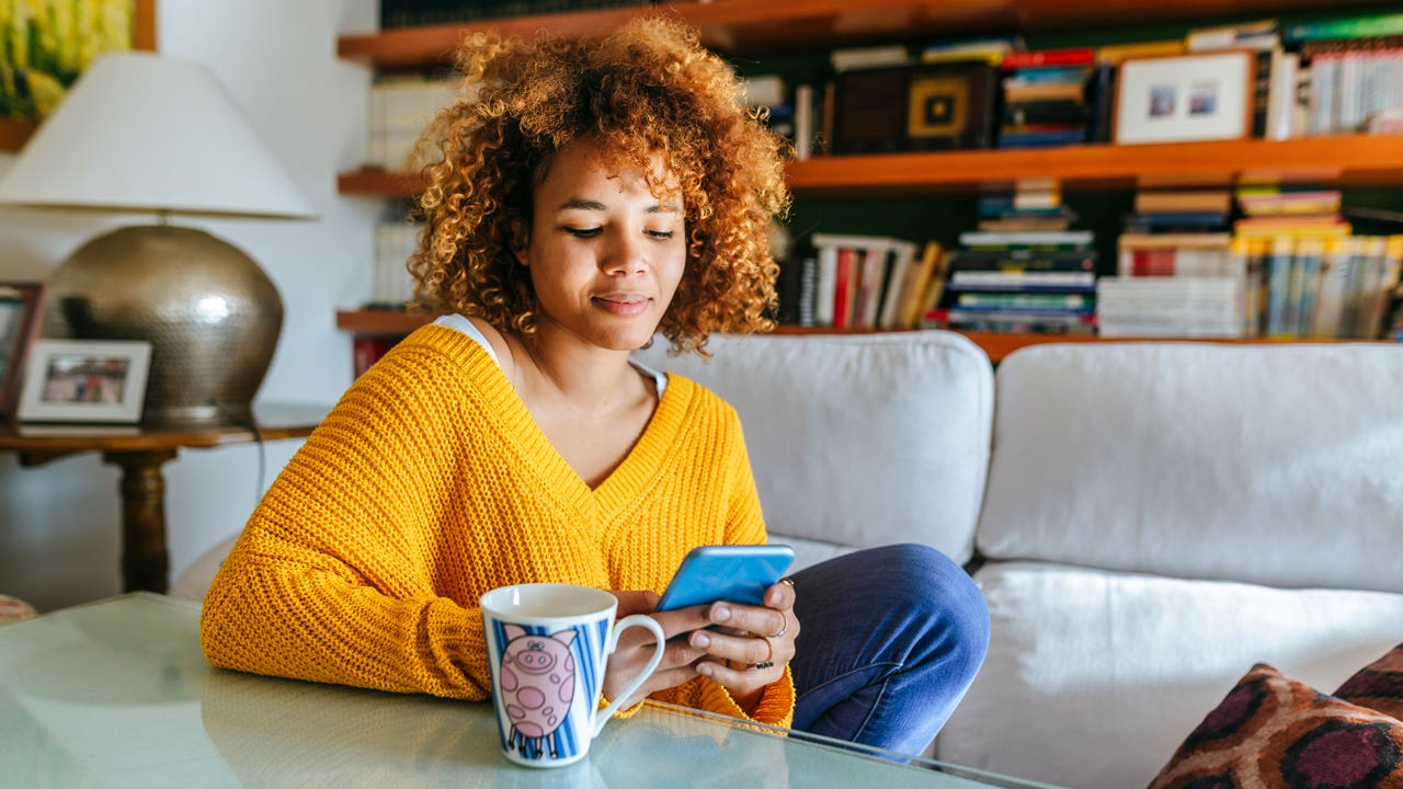 woman sitting at home looking at her phone