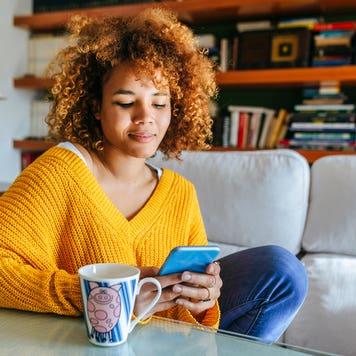 woman sitting at home looking at her phone