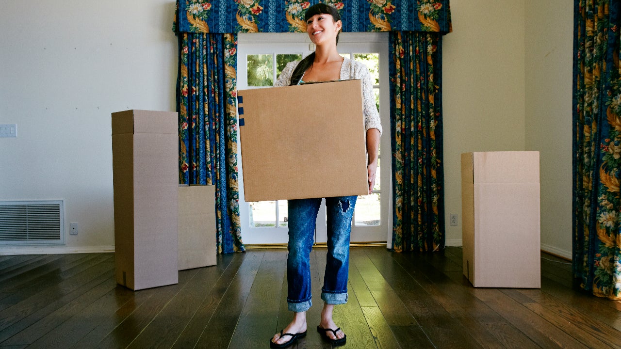 Mixed race woman carrying box in new home