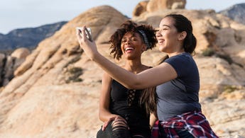 Two women taking a picture in a scenic nature landscape