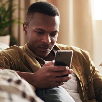 Man closely inspecting smartphone while holding credit card