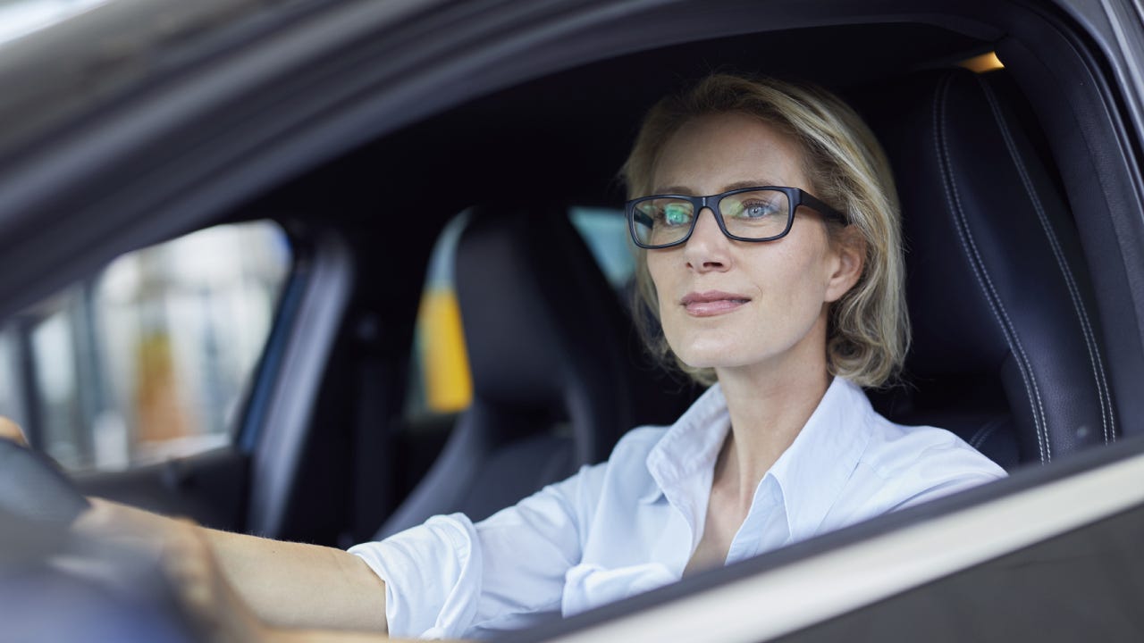 Blond businesswoman wearing glasses driving car