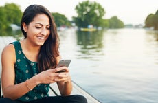A young woman looks at her phone on a jetty