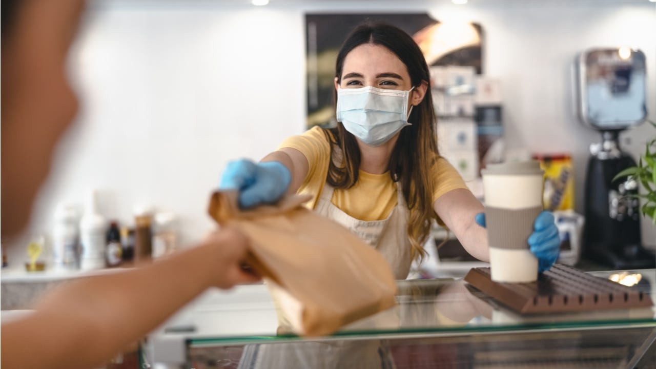 Masked worker hands customer takeout