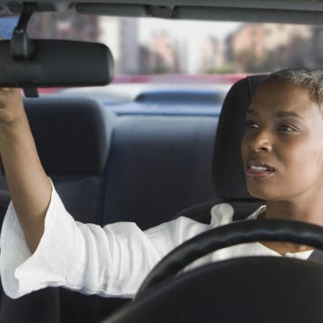 African woman in car adjusting mirror