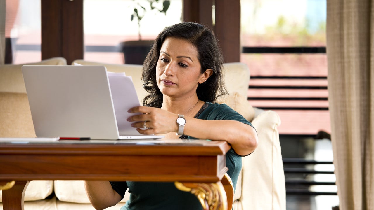 Frustrated woman reading document at home office