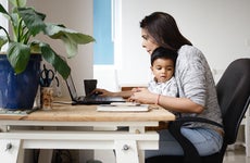woman holding a child and working online at home