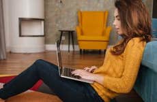 Young woman working on laptop on living room floor