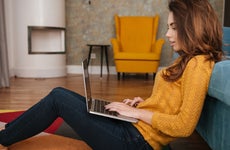 Young woman working on laptop on living room floor
