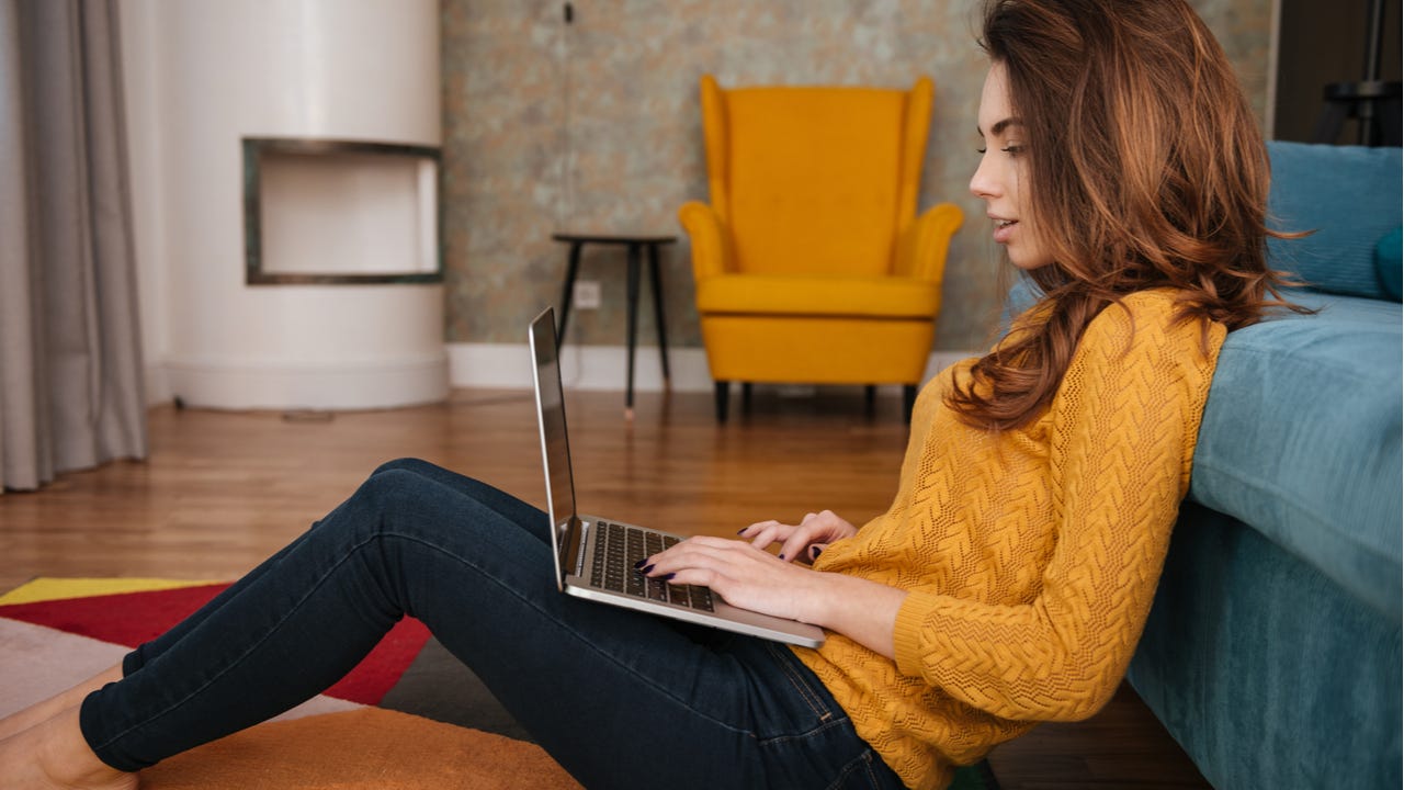 Young woman working on laptop on living room floor