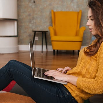 Young woman working on laptop on living room floor