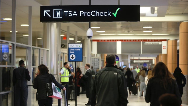 Travelers pass under a sign pointing toward a TSA Pre-Check checkpoint