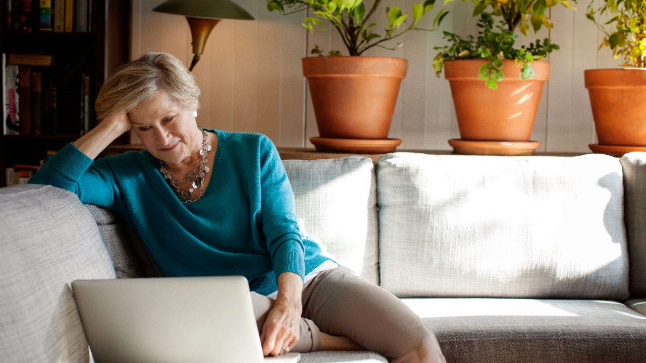 A senior woman works on a laptop.