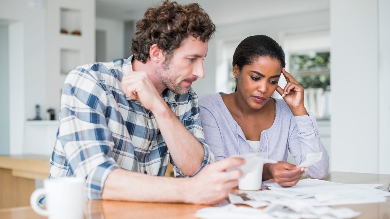 Tensed multi-ethnic couple reading bills at home
