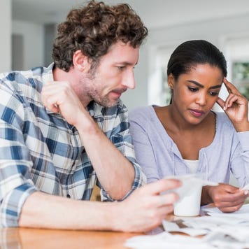 Tensed multi-ethnic couple reading bills at home