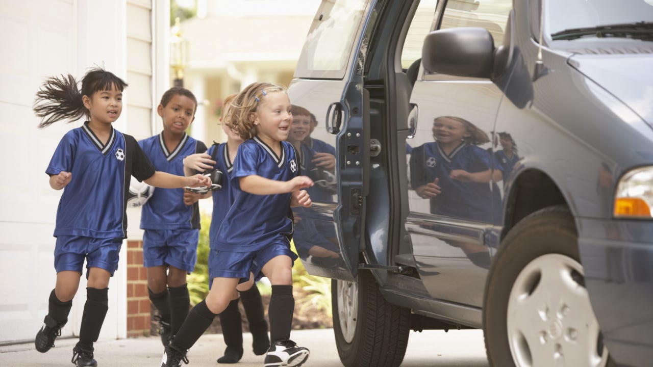 Children in soccer outfits getting into car