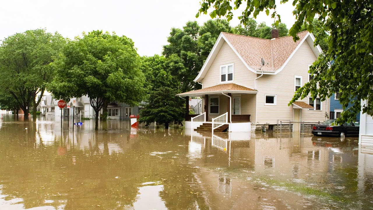 A flooded neighborhood with water reaching up to the upper decks of nearby houses.