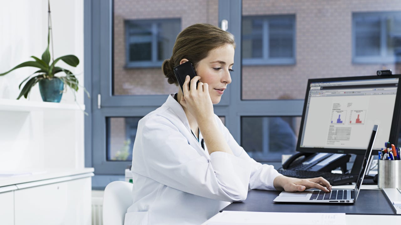 female doctor on smart phone, using laptop
